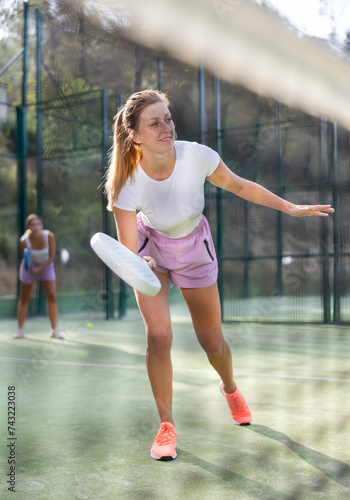 Padel game - woman with partners plays on the tennis court