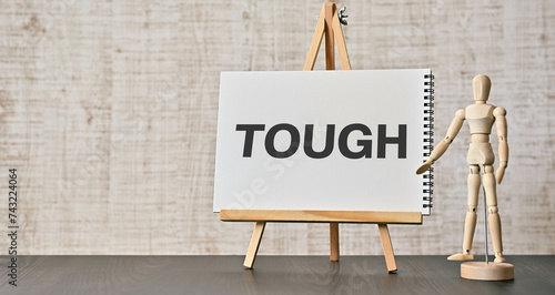 There is notebook with the word TOUGH. It is as an eye-catching image.