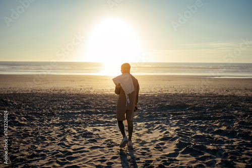 CHico joven tatuado y musculoso posando con ropa moderna en la playa al atardecer photo