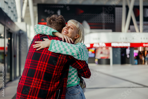 A happy young couple is hugging on a train station.