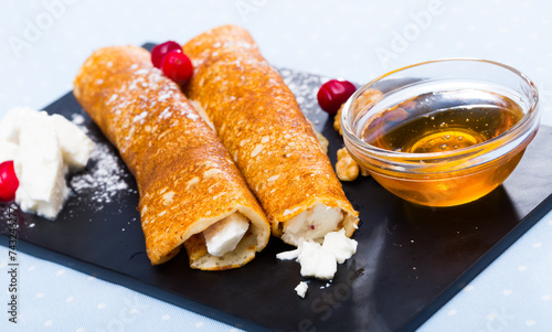 Bulgarian-style crepes Palatschinke with filling of soft cheese and walnuts with honey on black board photo