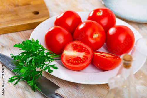 Ripe tomatoes on a plate during cooking, decorated with fresh parsley. Close-up image