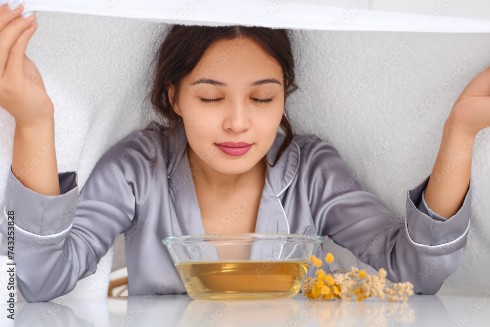 Young Asian woman doing steam inhalation at table in kitchen, closeup Young Asian woman doing steam inhalation at table in kitchen, closeup