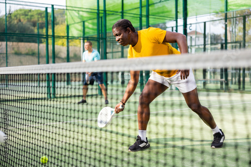 Sporty african american man playing padel tennis outdoor court