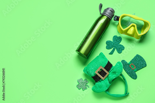 Diving mask, water bottle, leprechaun's hats and clovers on green background. St. Patrick's Day celebration photo