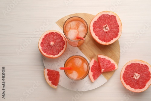 Tasty freshly made grapefruit juice and fruits on white wooden table, top view