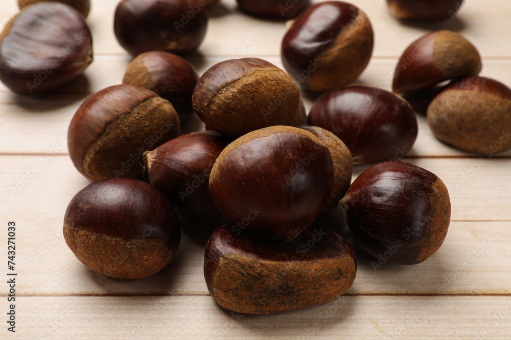 Sweet fresh edible chestnuts on light wooden table, closeup Sweet fresh edible chestnuts on light wooden table, closeup