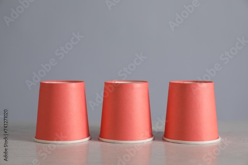 Shell game. Three red cups on light table