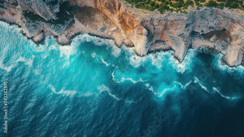 Clear blue waters gently kiss the rocky shore, creating a serene coastal landscape, where nature's beauty meets the calming textures of the sea