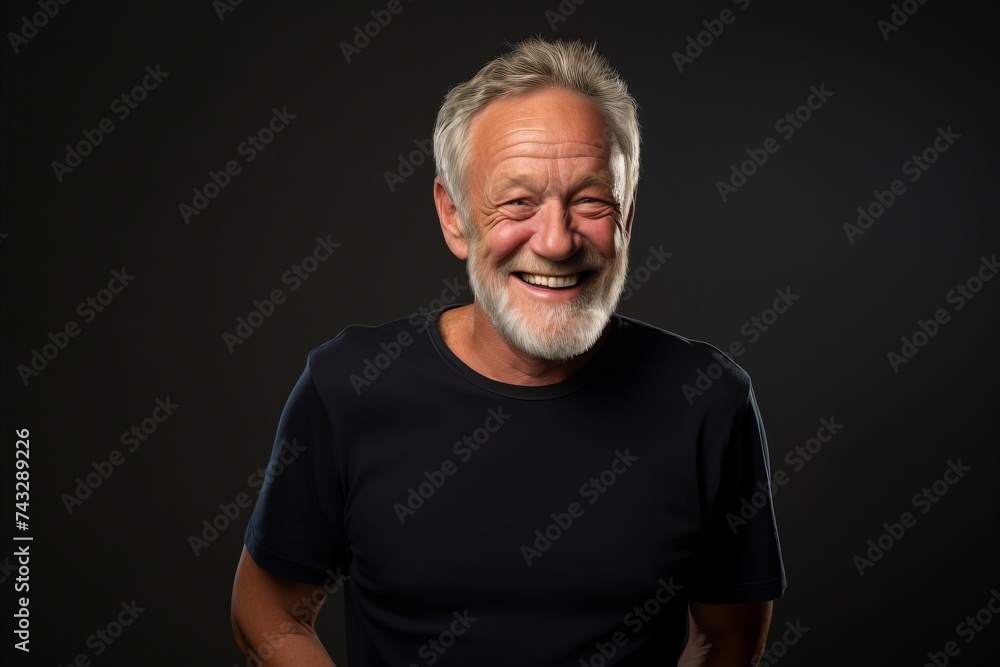 Portrait of a happy senior man laughing against a dark background.