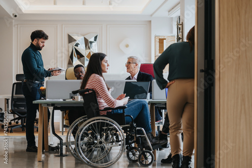 A modern office setting with multicultural team members and a colleague in a wheelchair, emphasizing diversity and inclusion at work. photo