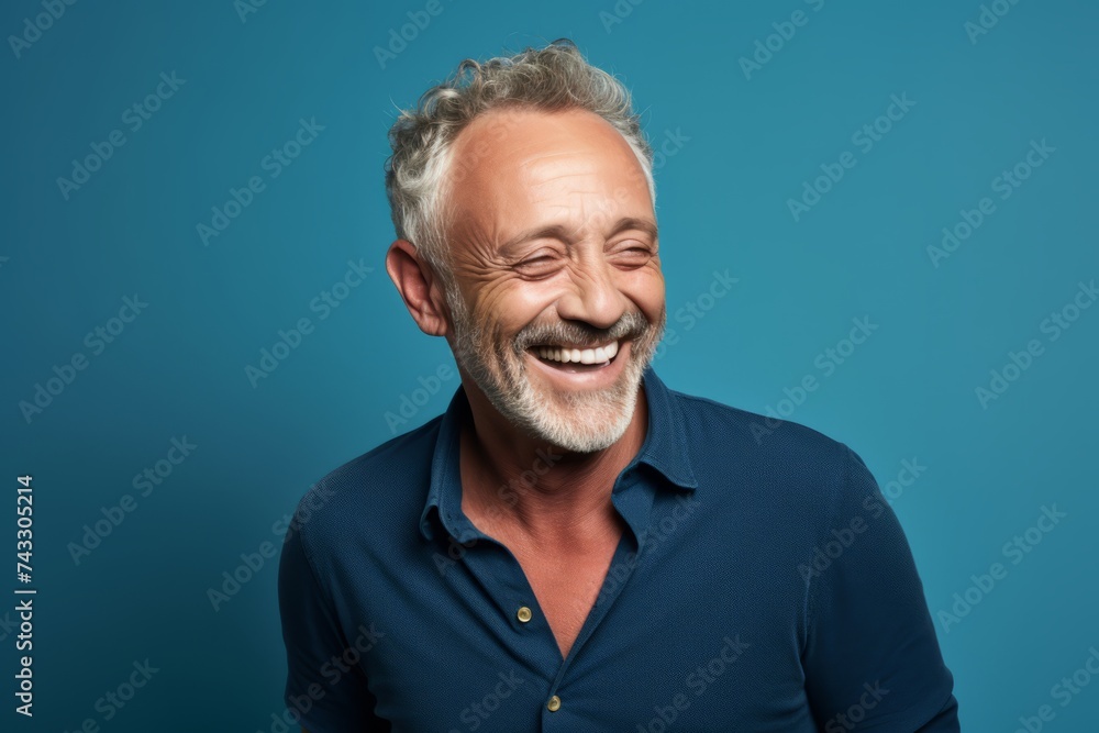 Portrait of a happy senior man laughing at the camera on a blue background Portrait of a happy senior man laughing at the camera on a blue background