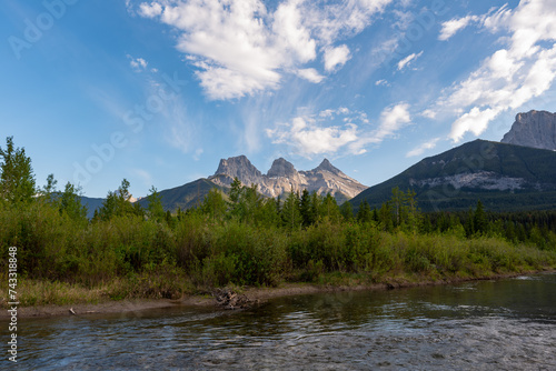 Incredible view of Three Sisters in Canada, Banff National Park with mountains reflecting in calm, lake, water below blue sky, pristine, perfect wilderness setting. 