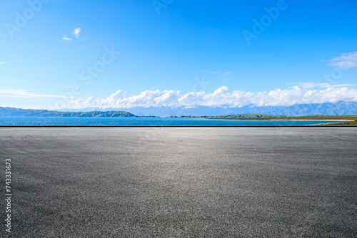 Fototapeta Naklejka Na Ścianę i Meble -  Asphalt road and blue lake with mountain nature landscape under blue sky
