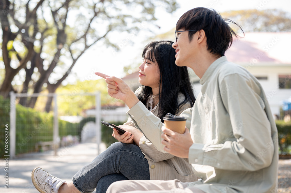 A positive Asian female is enjoying talking with her friend in a city park during her lunch break.