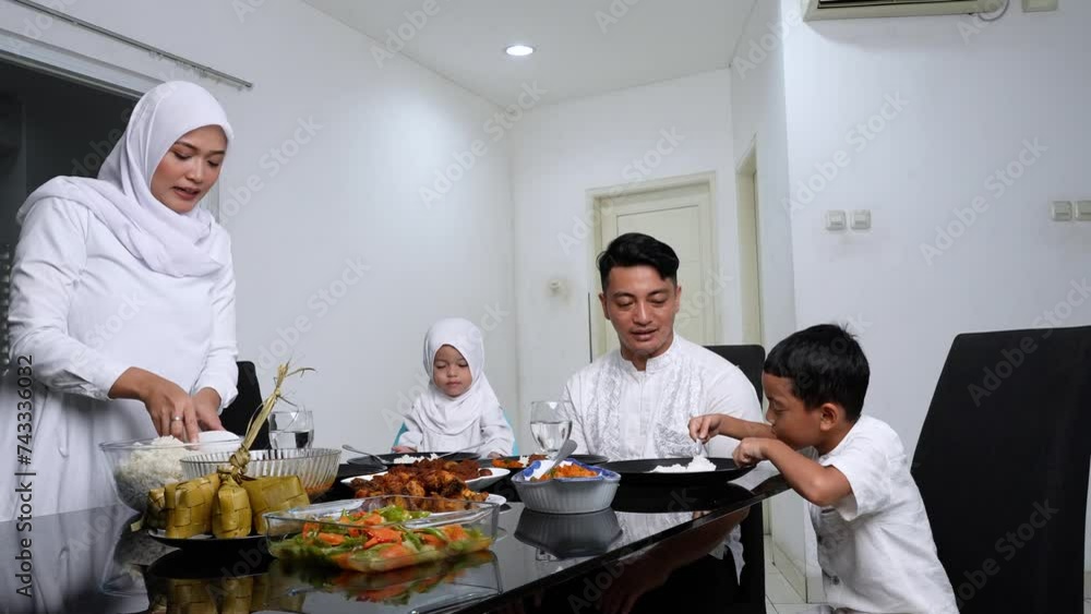 Happy family eating together in the dining room during ied mubarak - lebaran celebration Happy family eating together in the dining room during ied mubarak - lebaran celebration
