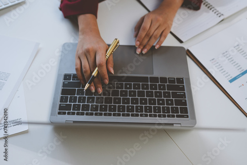 Asian businesswoman in formal suit. Cheerful, confident working with laptop computer to do business finance, taxes, reports, accounting, statistics and management concepts.