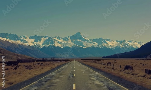 Journey into Serenity: A Road Leading to Snow-Capped Mountains under a Clear Sky, Bathed in Mystical Light