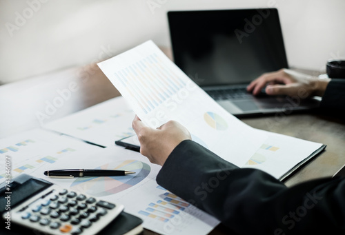The businessman hand sits at their desks and calculate financial graphs showing results about their investments, planning a successful business growth process © Orathai