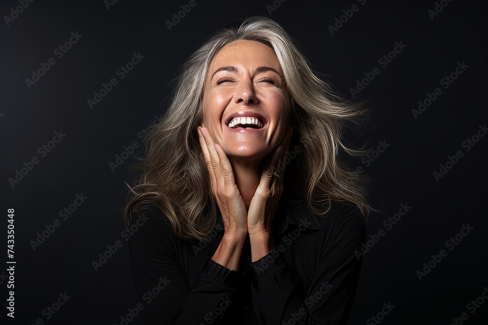 Portrait of a happy mature woman laughing and looking up on black background Portrait of a happy mature woman laughing and looking up on black background