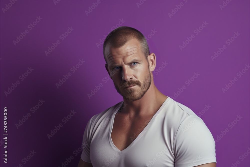 Portrait of a handsome man in a white T-shirt on a purple background