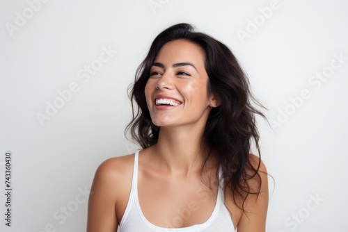 Portrait of a beautiful young woman laughing while standing against grey background