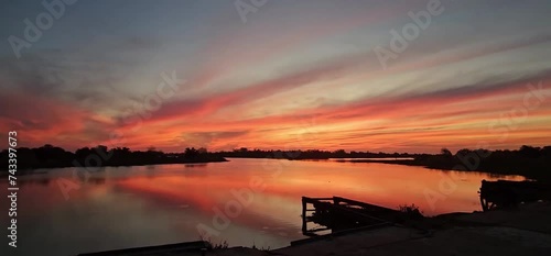 Impactante atardecer rojizo y reflejo del cielo en el río manso.  photo