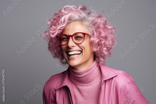 Portrait of a beautiful woman with pink hair and glasses against grey background