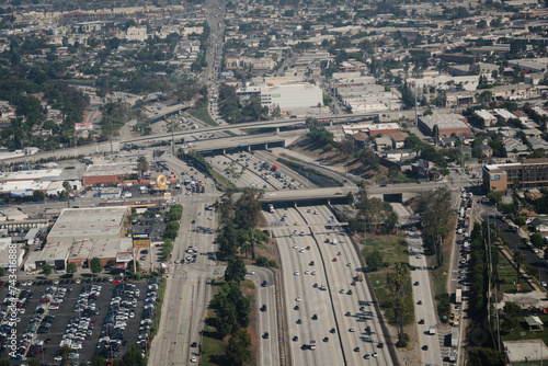 Aerial view of the freeway system in Los Angeles. Overpasses span several lanes, in a cityscape dominated by low-rise buildings.