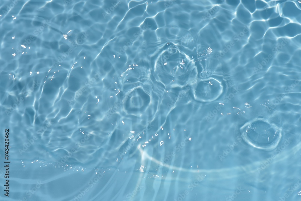 Obraz premium Blue water surface texture with ripples, splashes, and bubbles. Abstract summer banner background Water waves in sunlight with copy space cosmetic moisturizer micellar toner emulsion. Blue water wave.