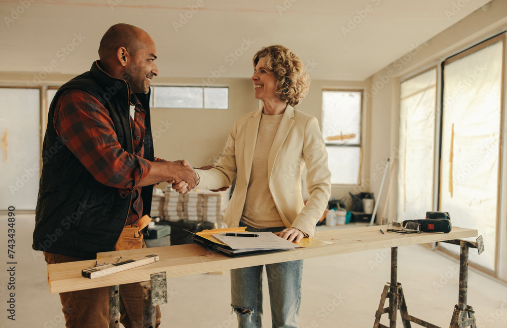 Successful partnership: Happy contractor and homeowner shaking hands in agreement for home renovation - obrazy, fototapety, plakaty 