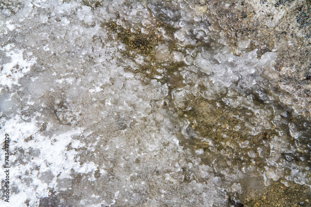 Obraz premium Melted snow and ice in early spring. Texture of wet snow on asphalt.