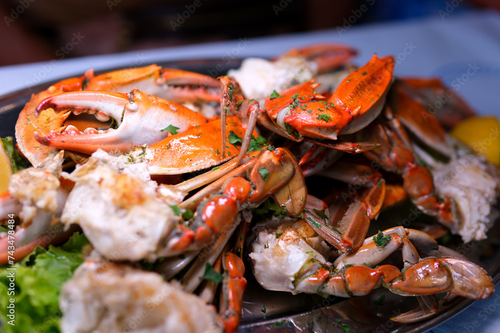 Seafood. Crabs tentacles on black plate with wite wine, lemon and herbs sauce on slate background. Top view. Seafood. Crabs tentacles on black plate with wite wine, lemon and herbs sauce on slate background. Top view.