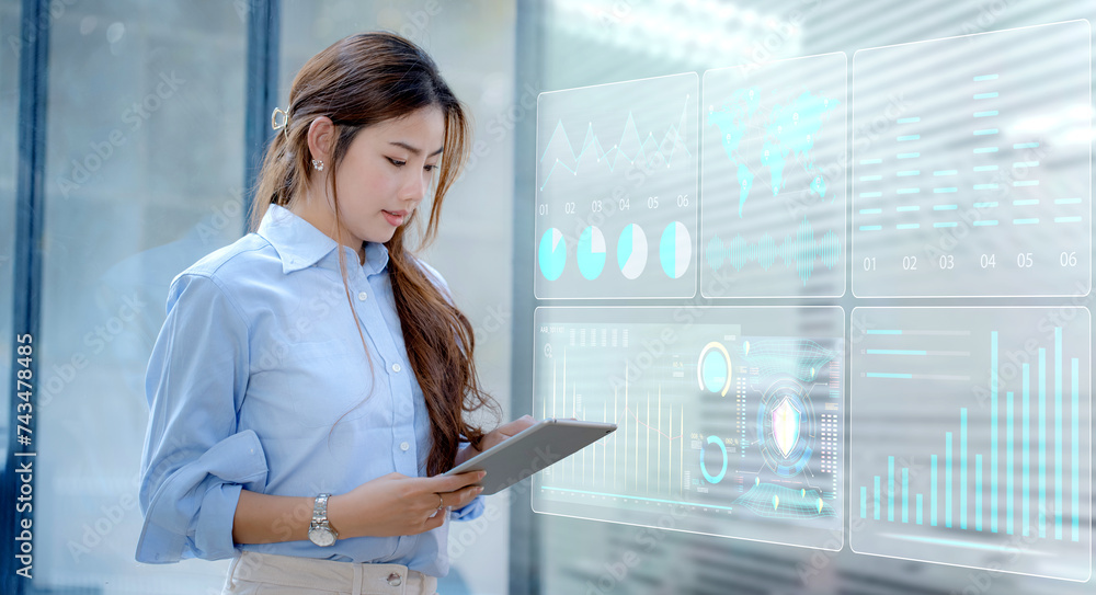 Happy asian young businesswoman using digital tablet with business finance chart dashboard on virtual screen and standing in office working space, Business finance data analytics and market concept. Happy asian young businesswoman using digital tablet with business finance chart dashboard on virtual screen and standing in office working space, Business finance data analytics and market concept.