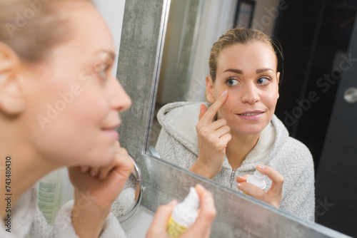 woman applying cream underneath her eye