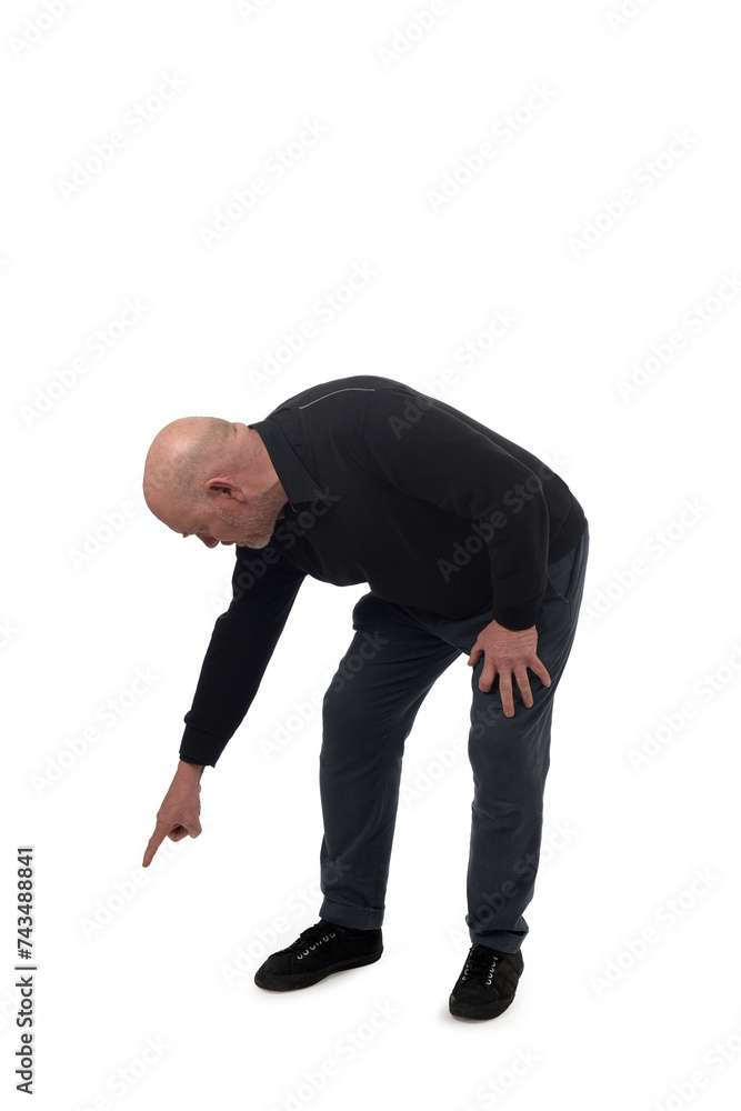 Naklejka premium side view of a crouching man pointing finger at the ground on white background