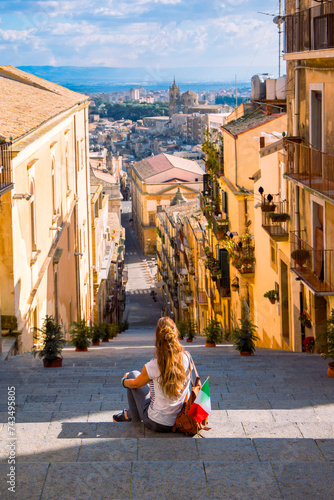 Woman tourist with italian flag sitting on stairs and enjoying town center of Caltagirone. Travel, tourism in Sicily island
