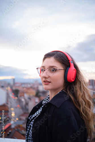 Sexy young woman listening to music on headphones in the city and smiles