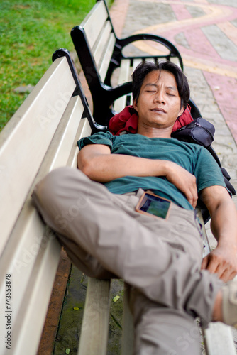 handsome man is sleeping on a park bench 