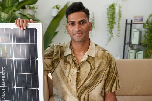 Portrait of smiling Indian man showing solar panel he ordered for his system