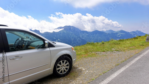 Traveling by car along mountain roads. The car is standing on the edge of a cliff. Magnificent views of the landscape  sky  mountain peaks. The concept of safety and insurance when traveling by car. 
