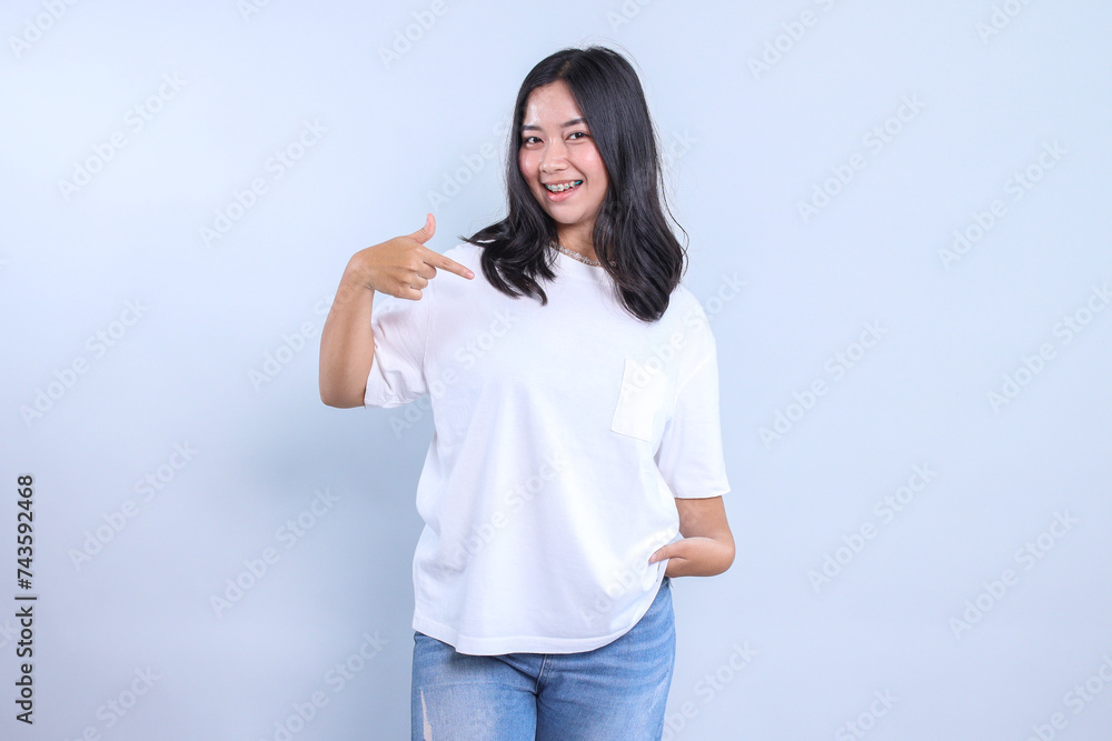 Young Asian girl wearing blank white t-shirt for mockup, pointing to the design Young Asian girl wearing blank white t-shirt for mockup, pointing to the design