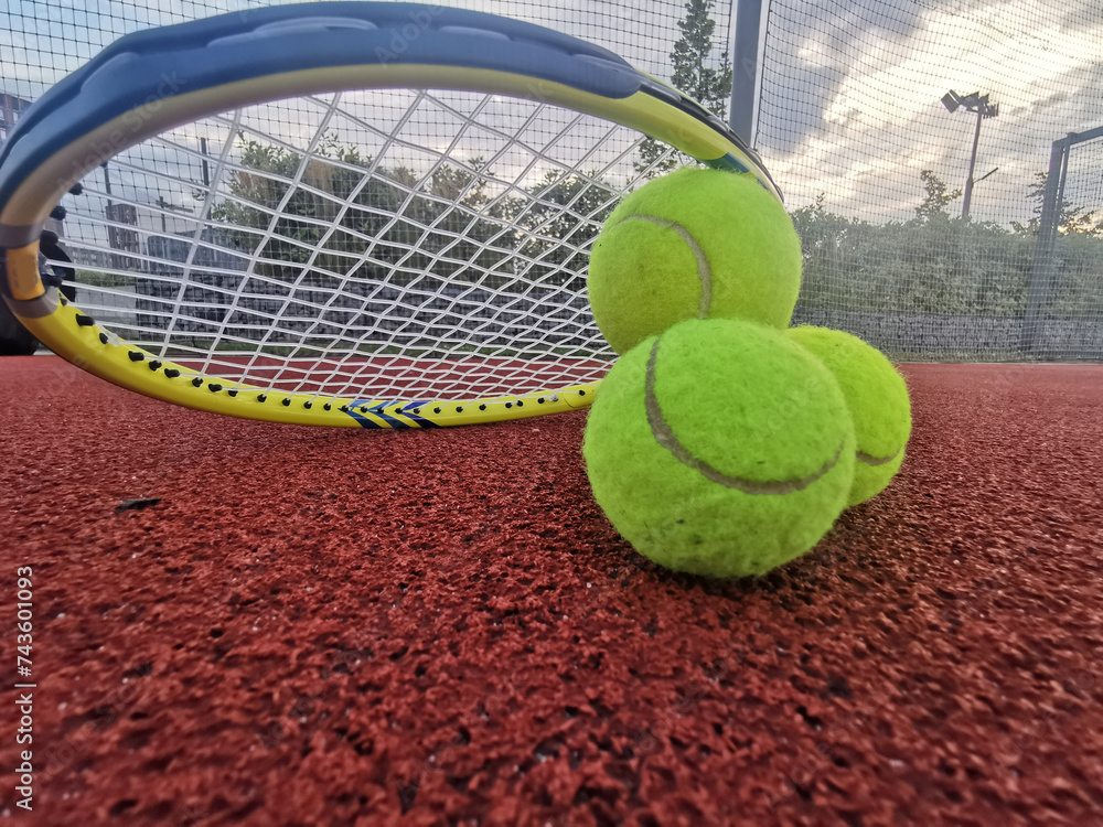 Tennis. Tennis ball and racket on a red background of tennis court with copy space. Sport and healthy lifestyle. The concept of outdoor game sports. 