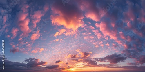 A panoramic view of a dreamlike sky with fluffy clouds tinged with pink and orange hues, illuminated by the soft, radiant light of a setting or rising sun. © ParinApril