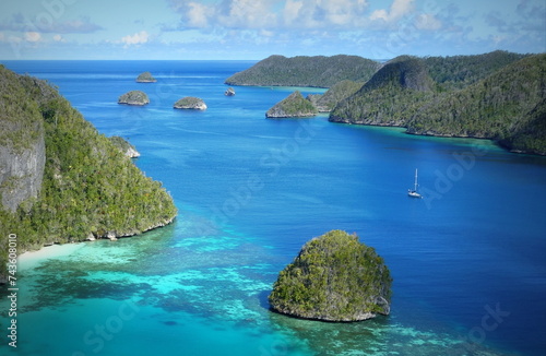 Tropical Indonesia Lagoon in Raja Ampat with small Sailboat in the bay