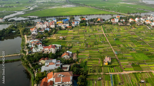 Aerial view of a vibrant agricultural landscape with lush green fields, water channels, and rural houses, illustrating sustainable farming practices in a peaceful countryside setting