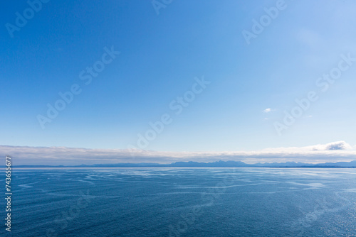 Calm dark blue sea with low clouds with land in the distance horizon