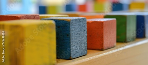A row of vibrant and diverse blocks are neatly arranged on top of a wooden table. Each block features a different color and shape, creating a visually appealing display. photo