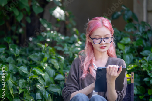 Cute pink hair girl drawing on digital tablet in garden, Woman Doing Freelance Work in Garden, woman with digital tablet with graffiti artwork