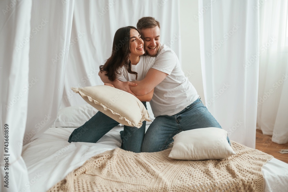 Soft pillows are in hands, playing. Young couple are together at home Soft pillows are in hands, playing. Young couple are together at home